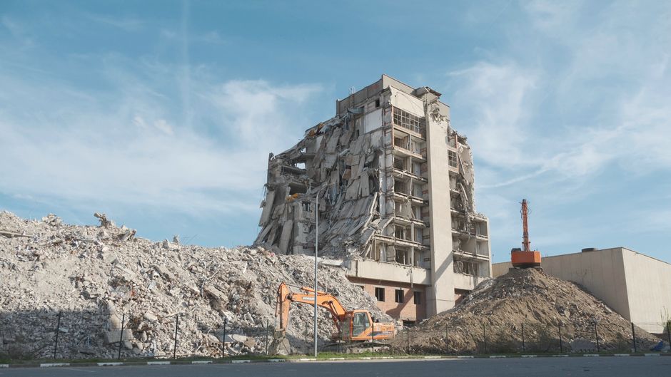 Urban demolition scene with a digger at a construction site.
